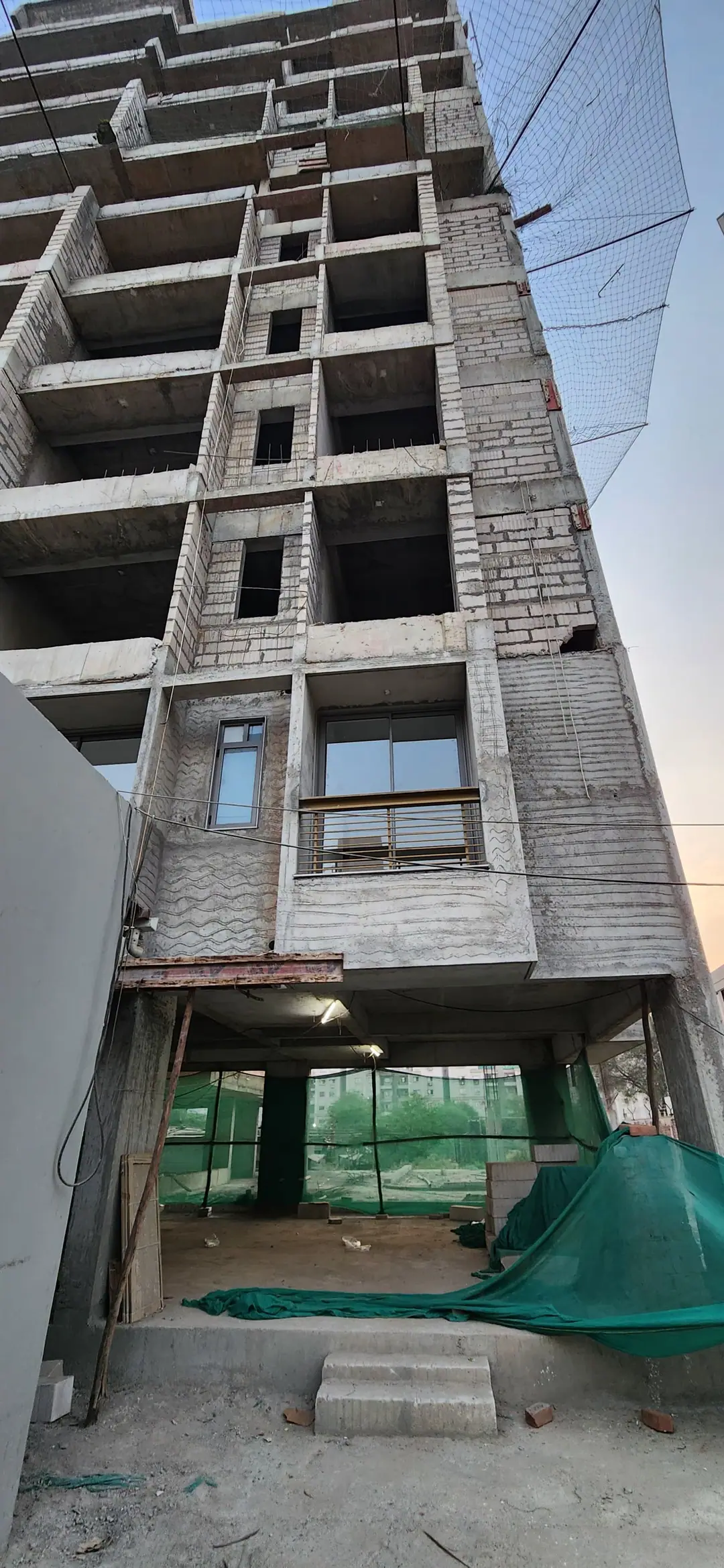 Multi-storey commercial building under construction, with window frames being fitted on the upper floors