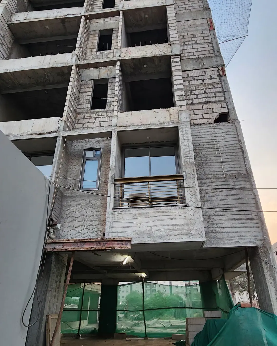 Multi-storey commercial building under construction, with window frames being fitted on the upper floors