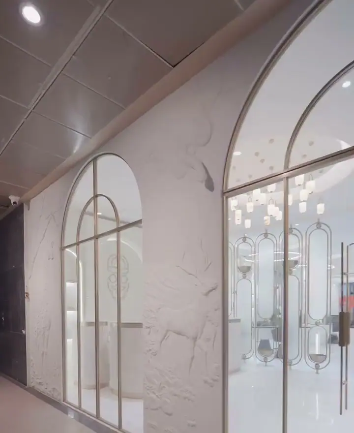 Salon frontage with tall arched glazing in slim champagne-coloured frames