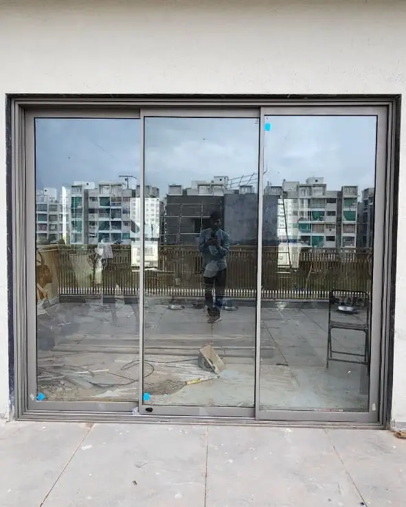 Three-panel aluminium sliding door opening onto a rooftop terrace, with the site still in progress