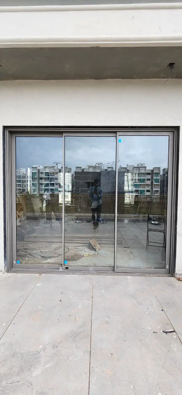 Three-panel aluminium sliding door opening onto a rooftop terrace, with the site still in progress